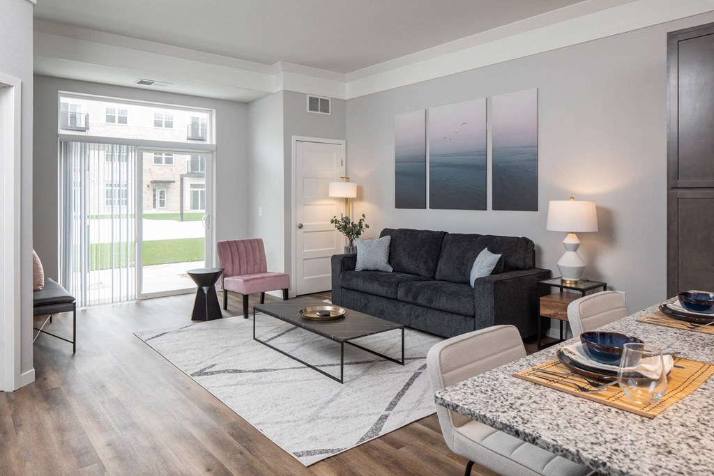 A modern living room with a grey couch, a red chair, and a marble table at The Edison at Woodbury, Woodbury, MN