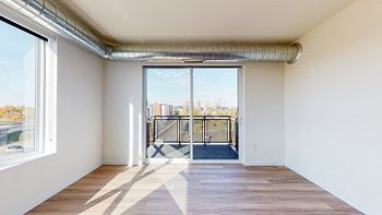 A room with a view of a balcony through a sliding glass door at The Bessemer at Seward Commons Apartments, Minneapolis