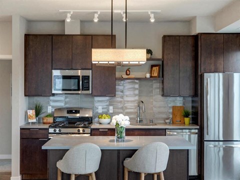 A modern kitchen with dark brown cabinets and stainless steel appliances.