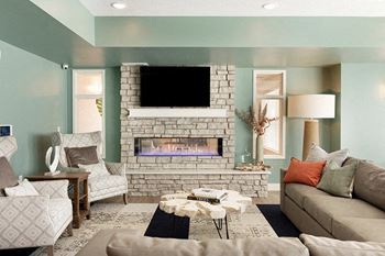 A living room with a fireplace and a flat screen TV mounted above it at The Barnum Apartments, White Bear Lake, Minnesota