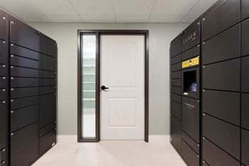 A hallway with a white door and a wall of lockers on the left at The Barnum Apartments, White Bear Lake, Minnesota