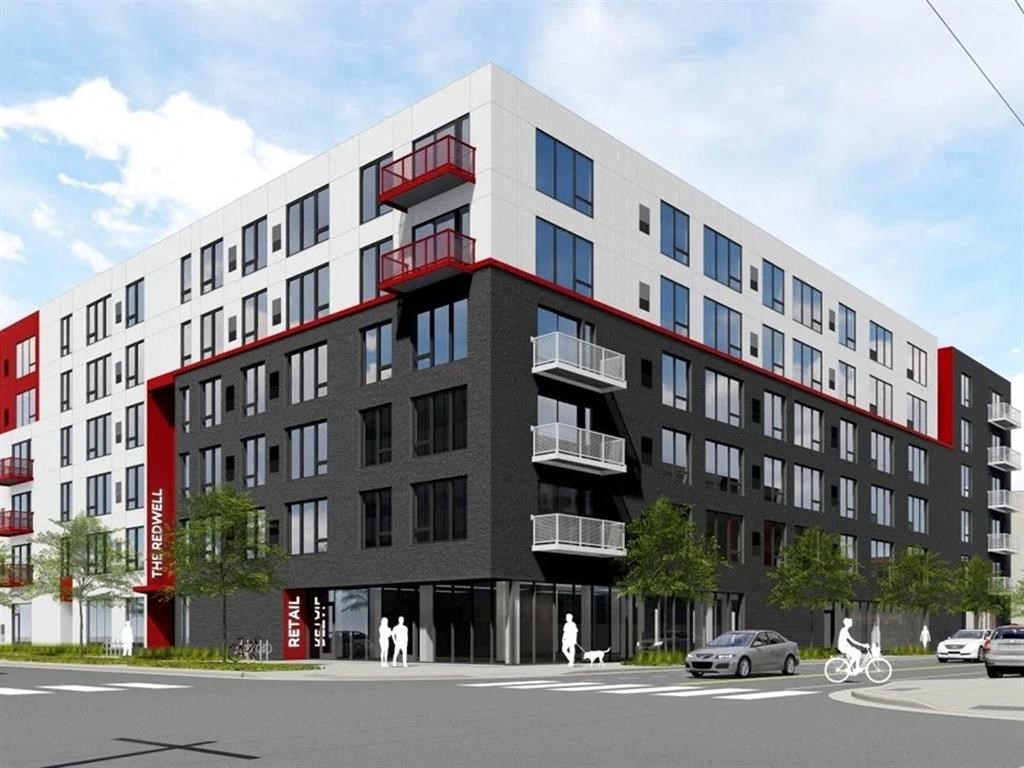 A modern multi-story building with a red and black facade and a sign that reads "The Rowell".