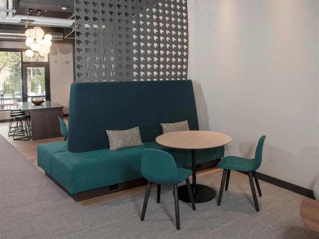 A modern living room with a green sofa, a round table, and a patterned wall.