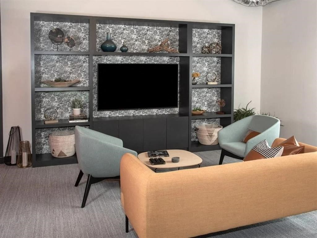 A living room with a television, two chairs, and a coffee table.