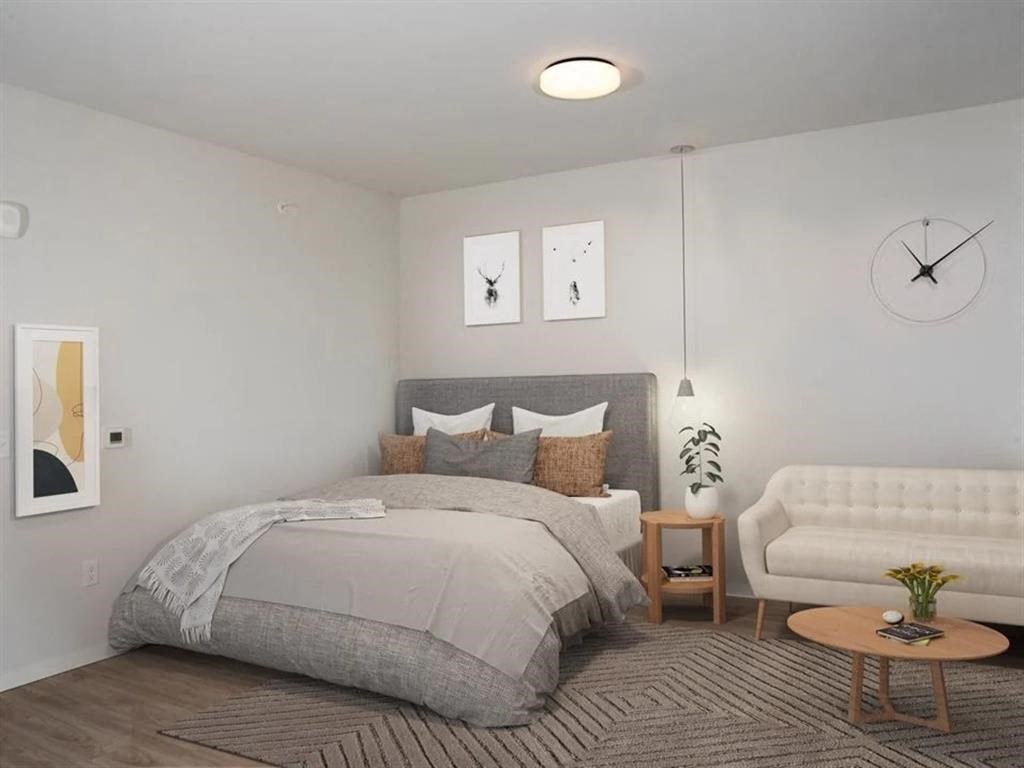 A bedroom with a large bed and a white couch.