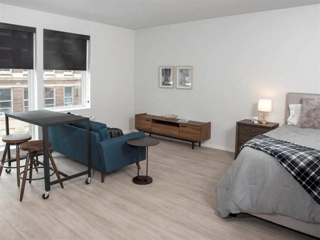 A bedroom with a bed, a sofa, a table, and a window.