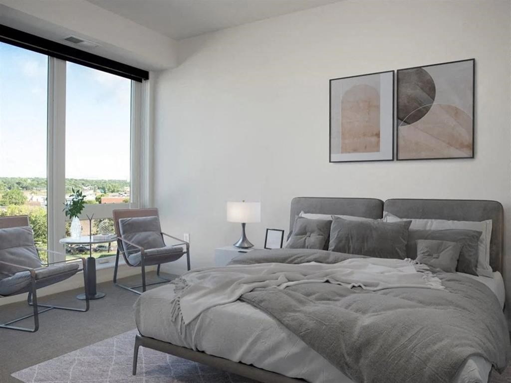 A bedroom with a large bed and a chair.