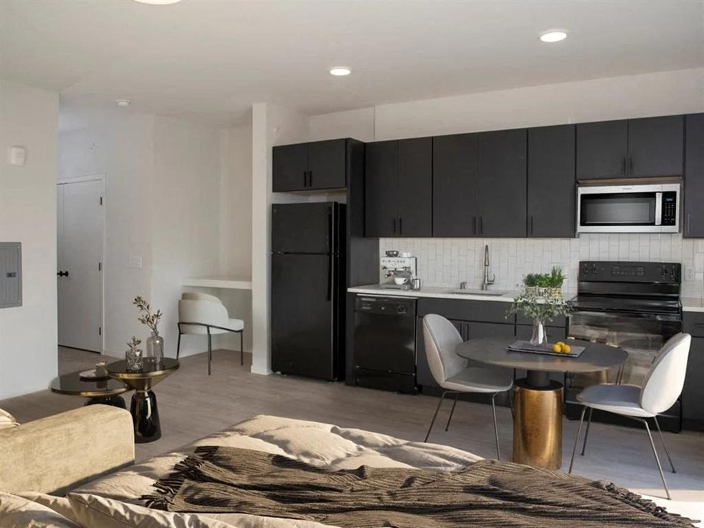 A modern kitchen with a black refrigerator and white cabinets.