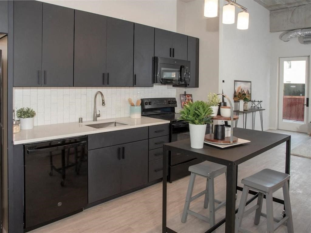 A kitchen with black cabinets and a white countertop.