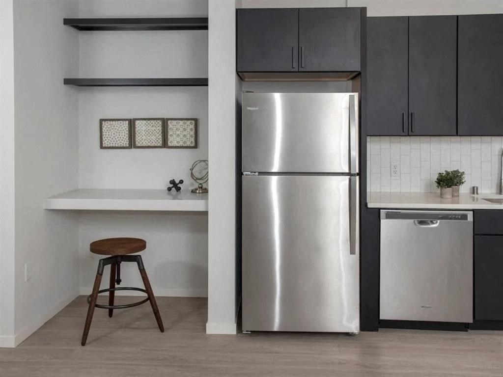 A kitchen with a stainless steel refrigerator and a bar stool.