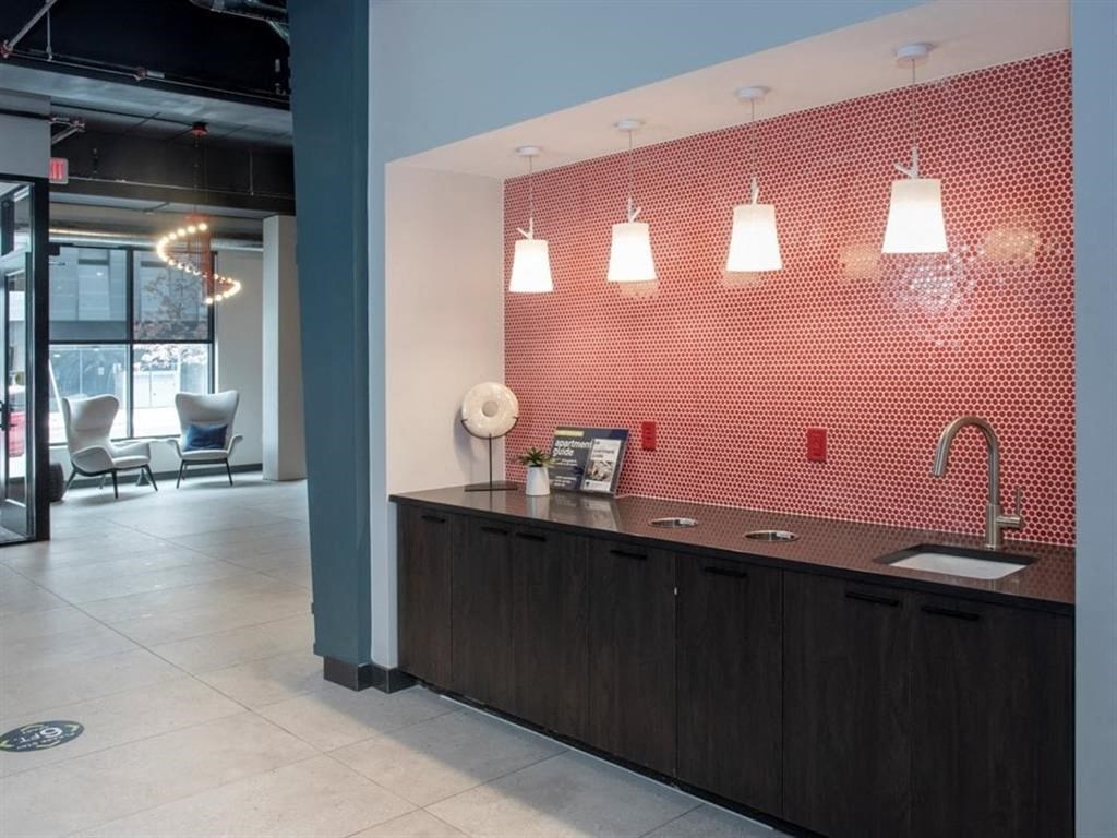 A modern kitchen with a red backsplash and wooden cabinets.