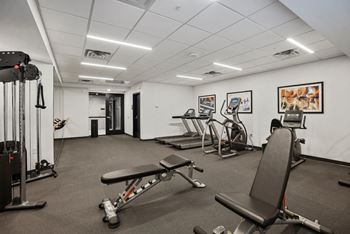 A gym with a variety of equipment including treadmills, weights, and exercise machines.