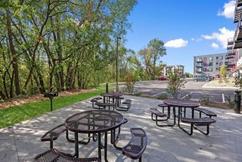 A sunny day at a park with picnic tables and chairs.