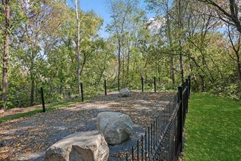 A black fence surrounds a grassy area with a large rock in the middle.