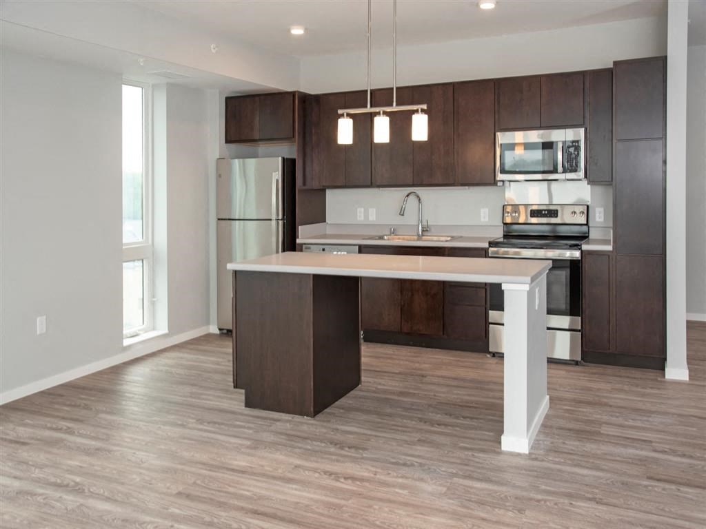 A modern kitchen with a center island and dark wood cabinets.