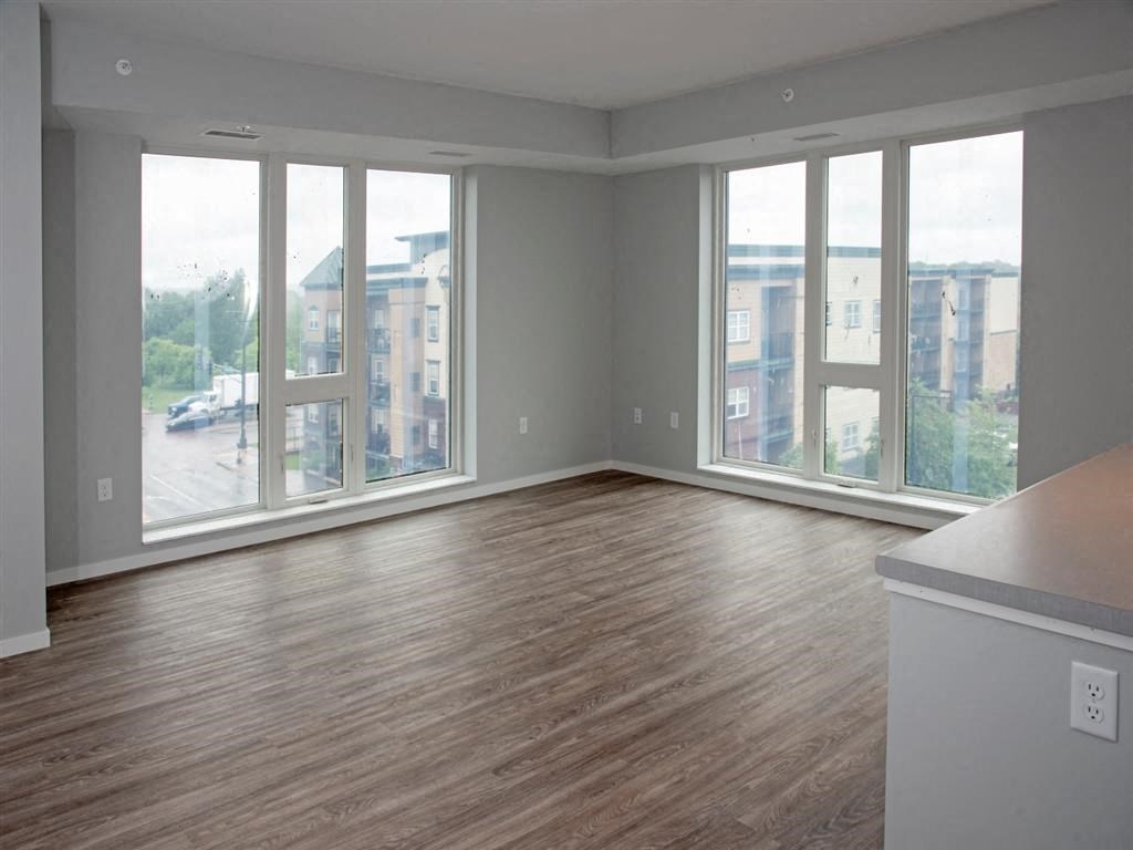 A room with wooden floors and large windows overlooking a street.