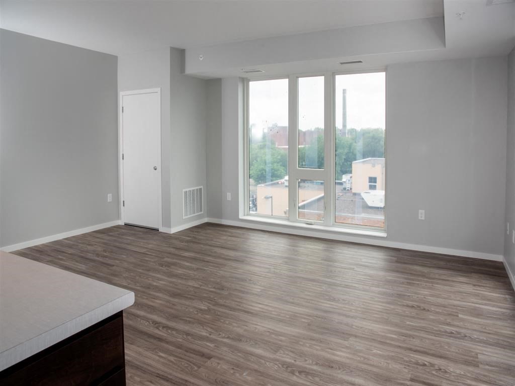 A room with a wooden floor and a large window overlooking a parking lot.