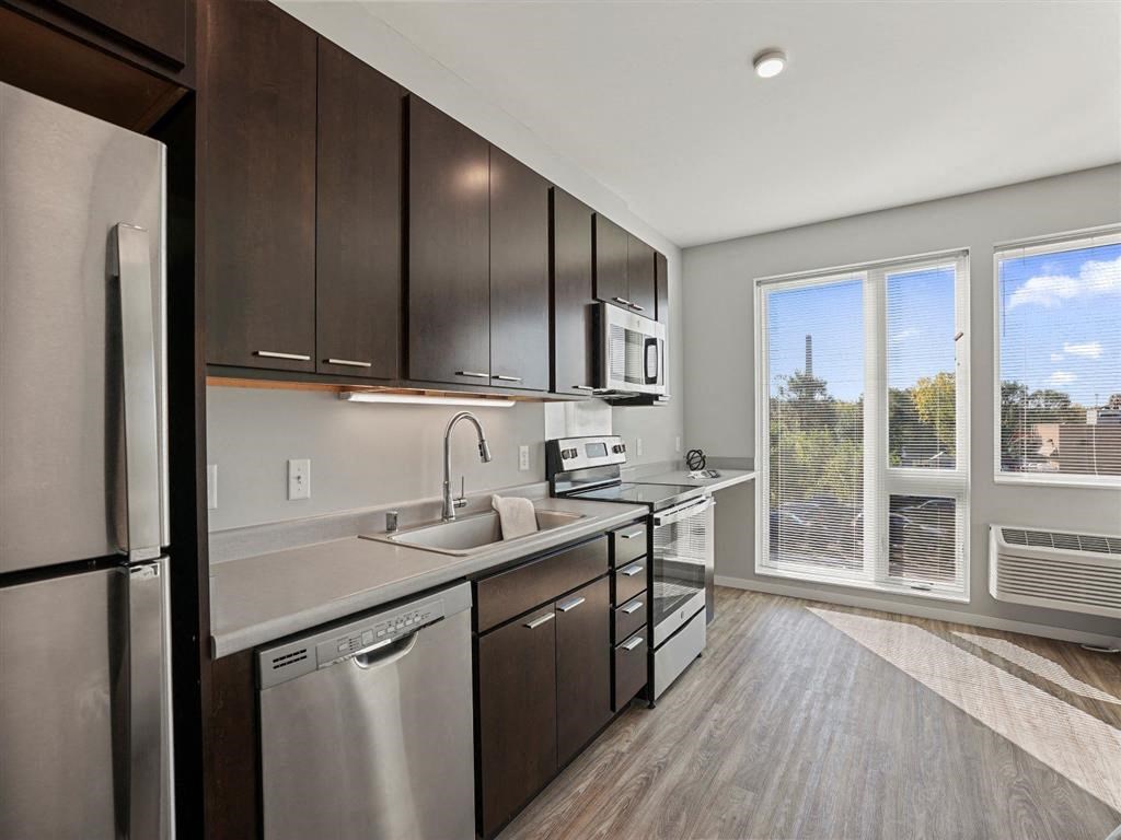 A modern kitchen with dark wood cabinets and stainless steel appliances.