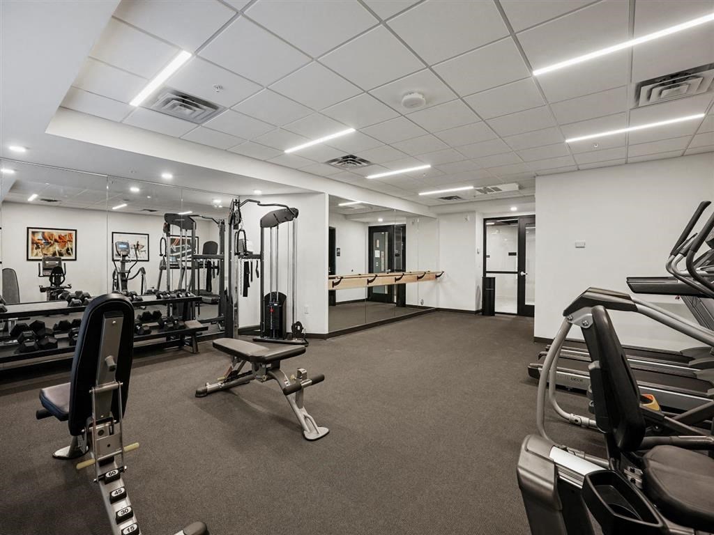 A gym with a variety of equipment including a treadmill, weights, and a bench.