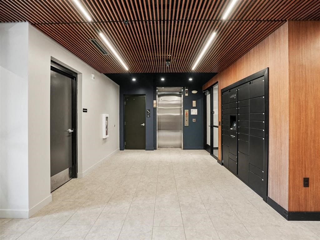 A long hallway with doors on both sides and a light brown ceiling.