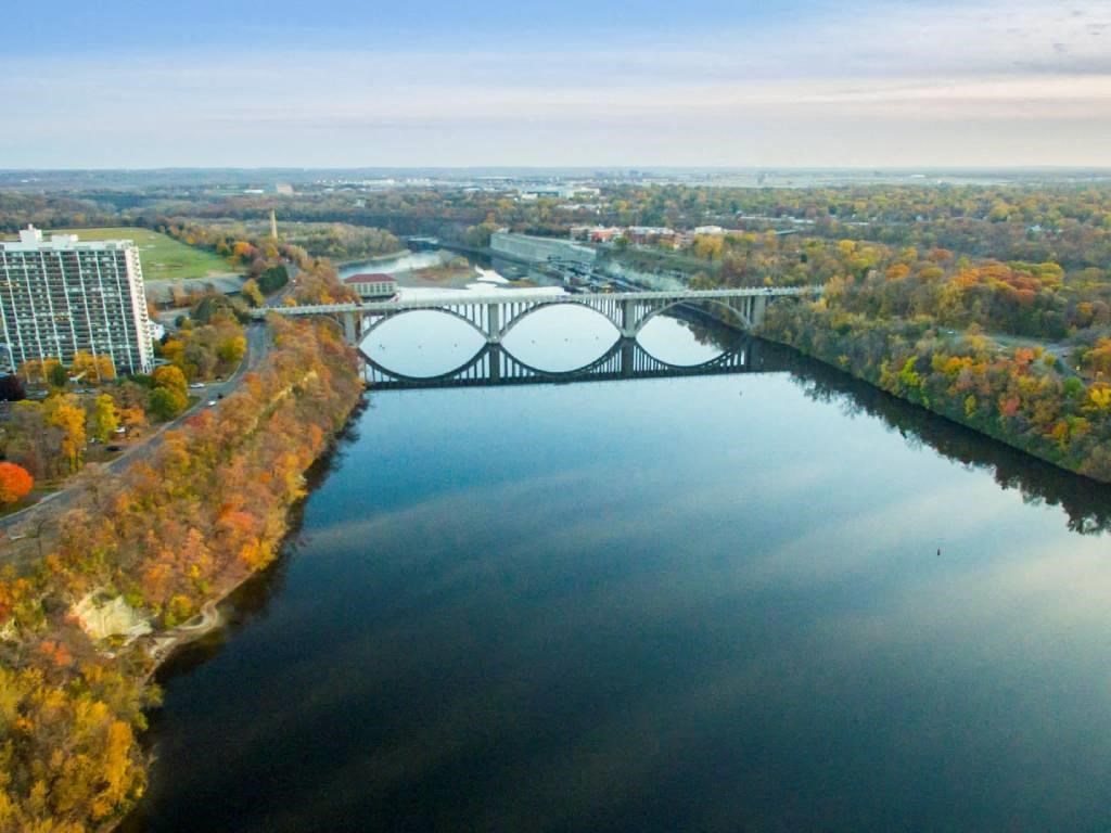 A bridge spans a river in a city with trees in the background.
