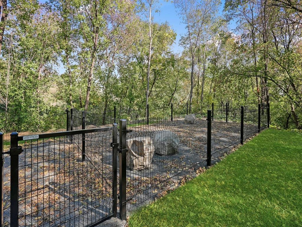 A black fence surrounds a tree stump in a grassy area.