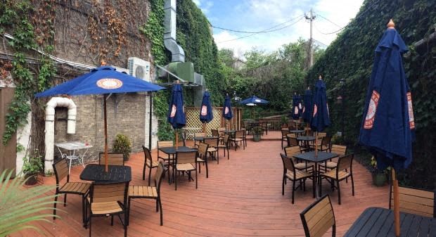 A patio with tables and chairs under blue umbrellas.