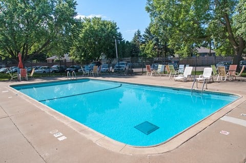 a swimming pool with chairs around it and trees