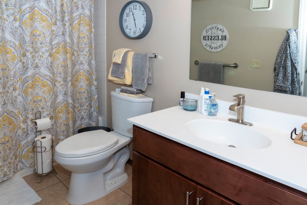 a bathroom with a toilet sink and mirror and a shower curtain