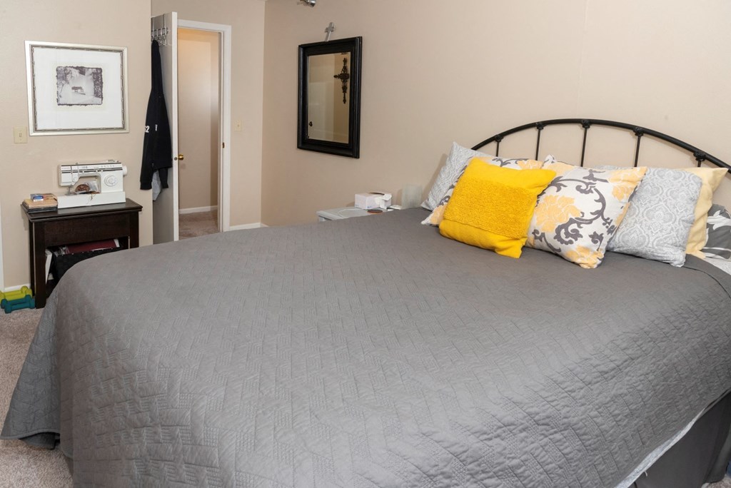 a bedroom with a gray bed and yellow pillows