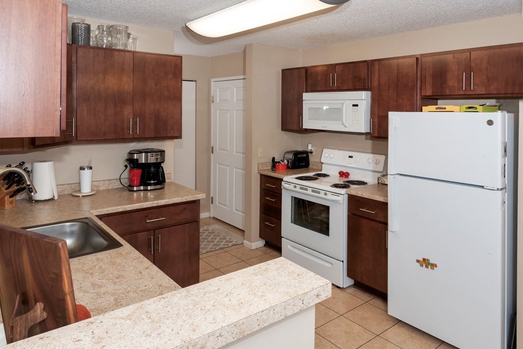 a kitchen with white appliances and counters and wooden cabinets