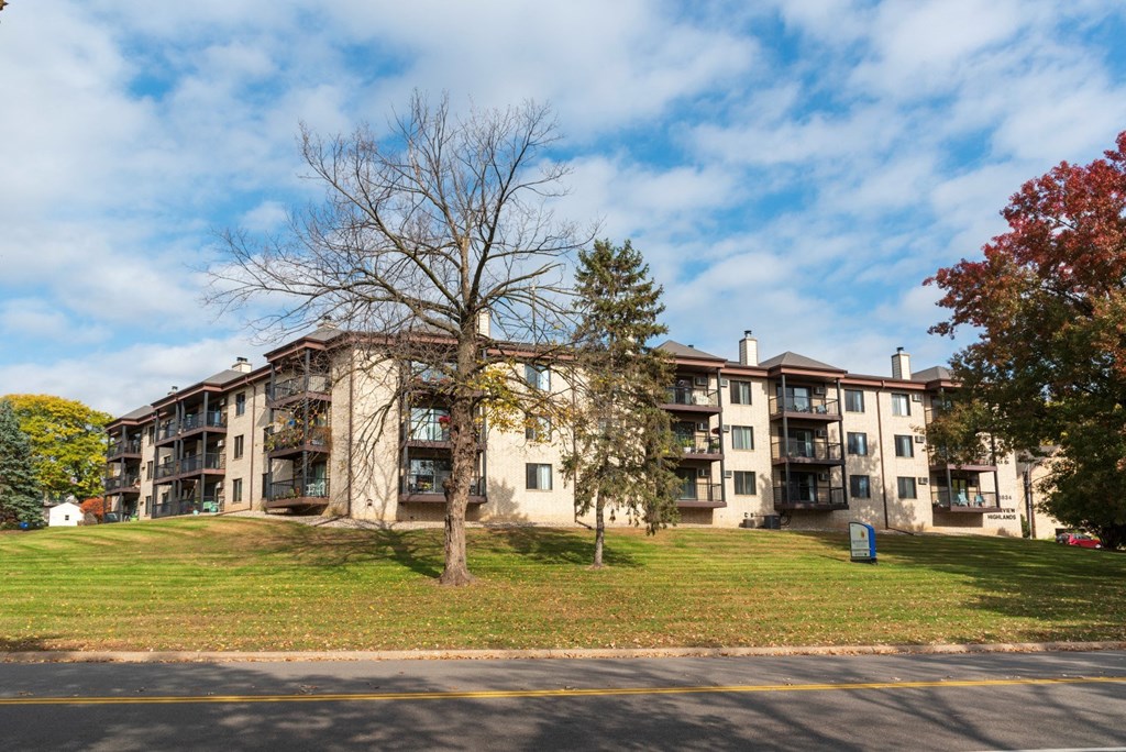 exterior view of an apartment building on a hill with a tree