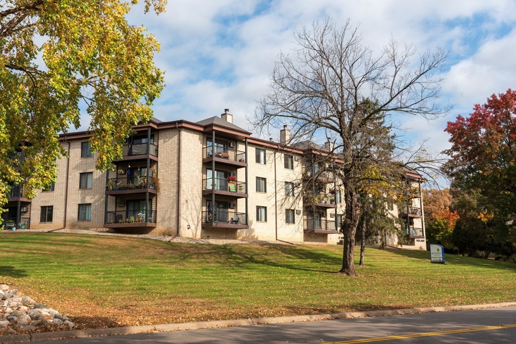 an apartment building on a hill with a tree in front of it