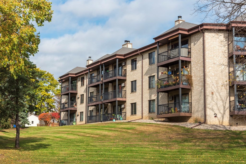 an apartment building on a hill with a green lawn
