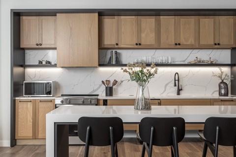 A modern kitchen with wooden cabinets and a marble backsplash.