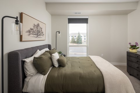 A bedroom with a large bed and a painting on the wall.