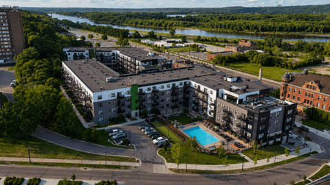 A large apartment complex with a swimming pool and a river in the background.