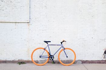 an orange and blue bike parked next to a white brick wall at Tyler Street Stacks, Minneapolis