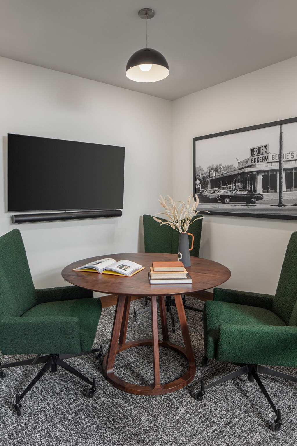 a room with a table with a book on top of it and three green chairs around it