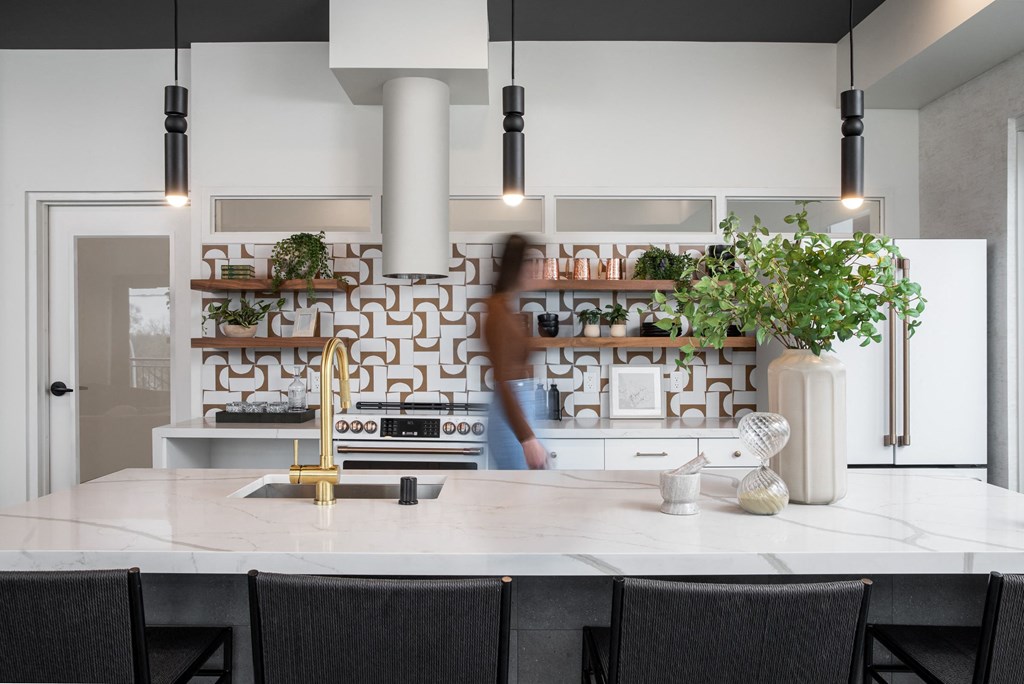 a kitchen with a white counter top and black chairs
