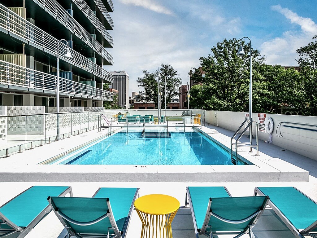 a pool on the rooftop of an apartment building with tables and chairs