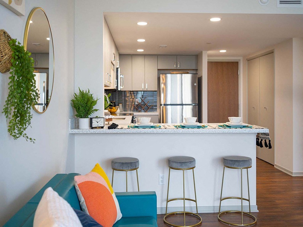 a kitchen with a bar and stools in a living room