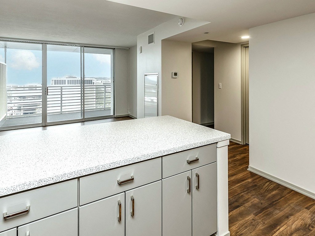 an empty kitchen with white cabinets and a large window
