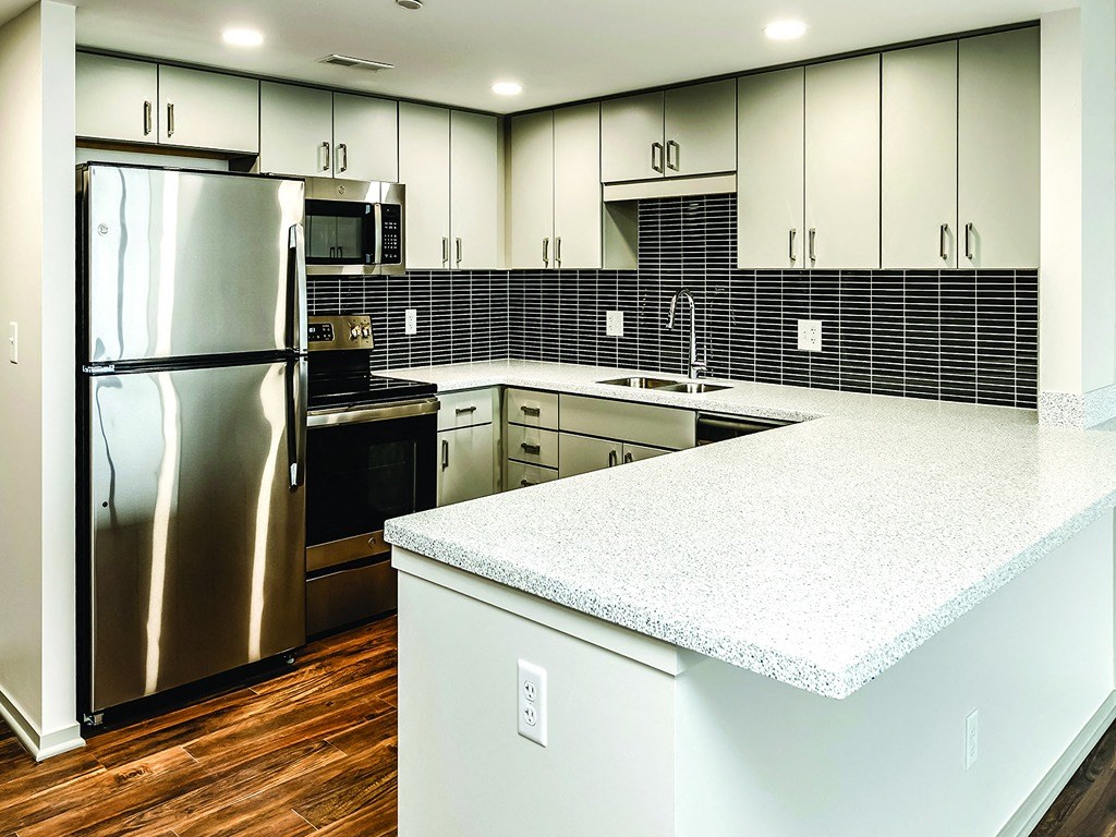 a kitchen with white counter tops and a stainless steel refrigerator