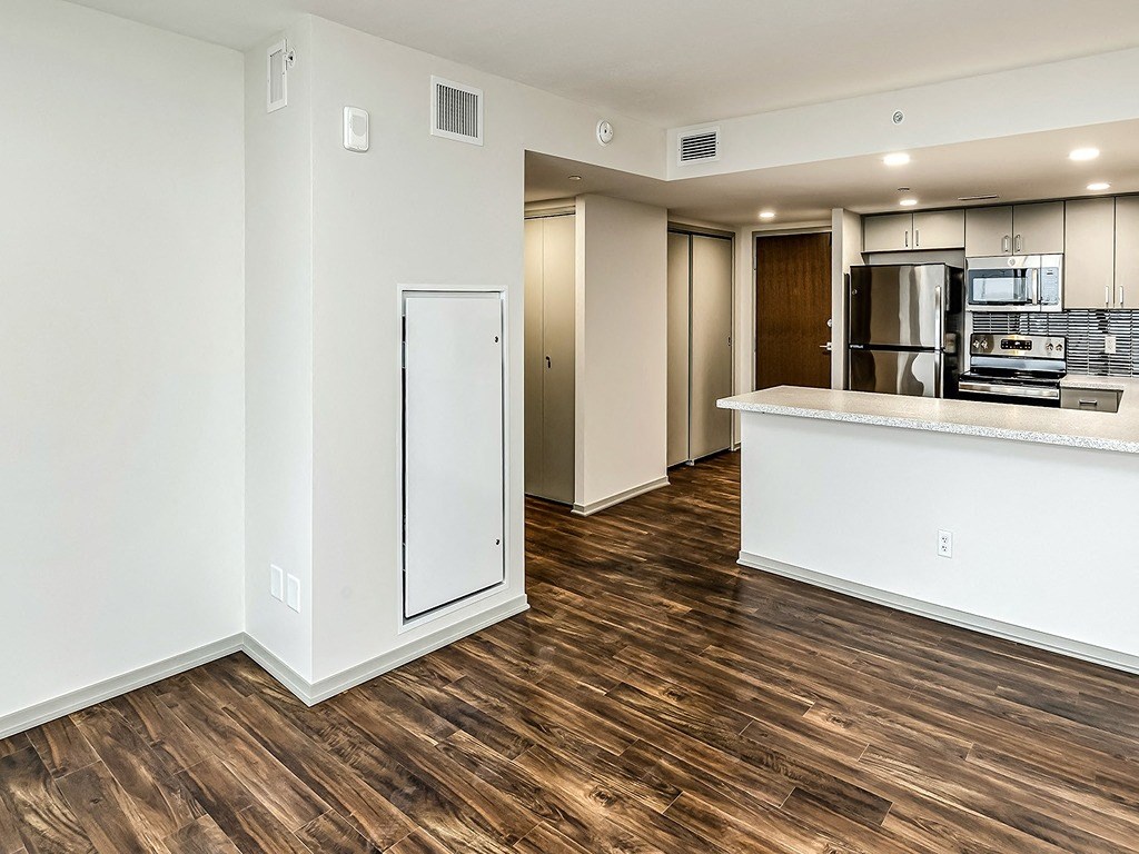 an empty living room and kitchen with a refrigerator and microwave