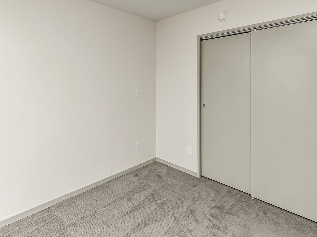an empty bedroom with a door to the closet