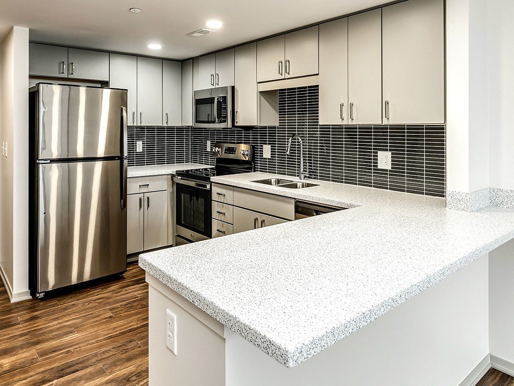 a kitchen with white counter tops and a stainless steel refrigerator