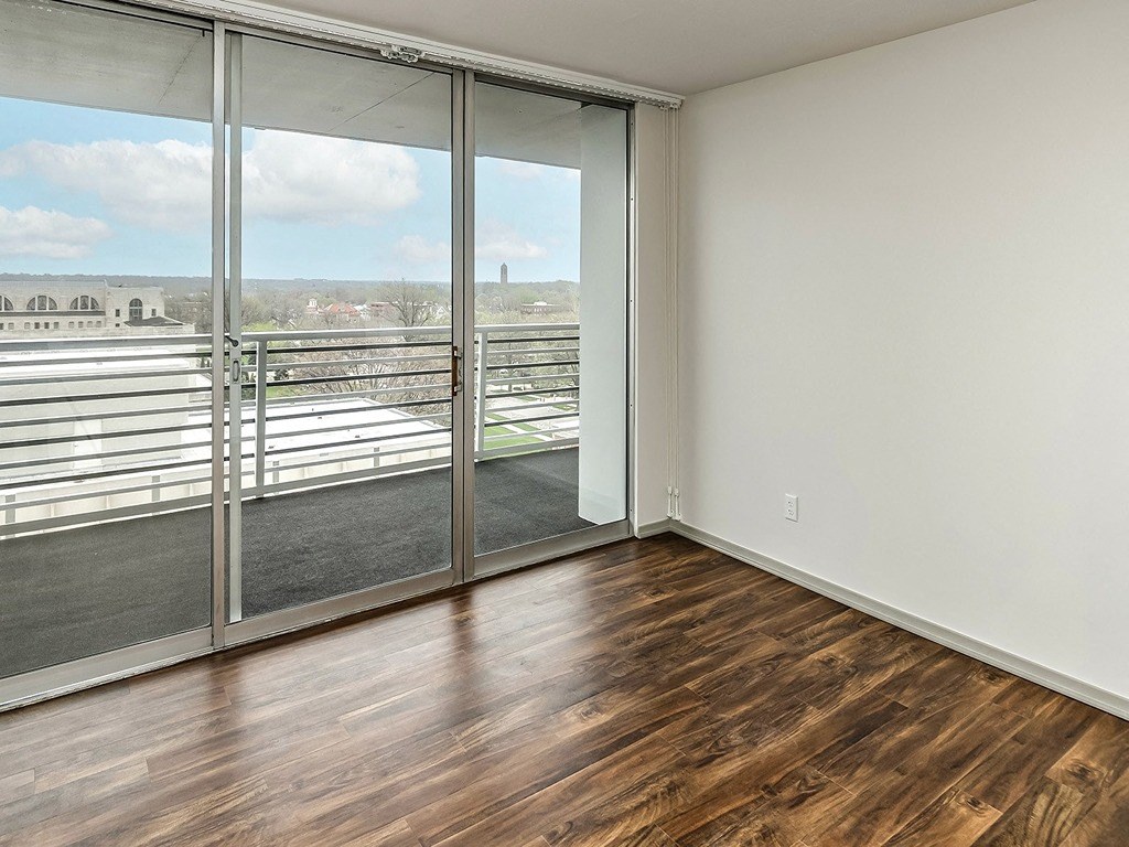 an empty living room with wood flooring and a balcony