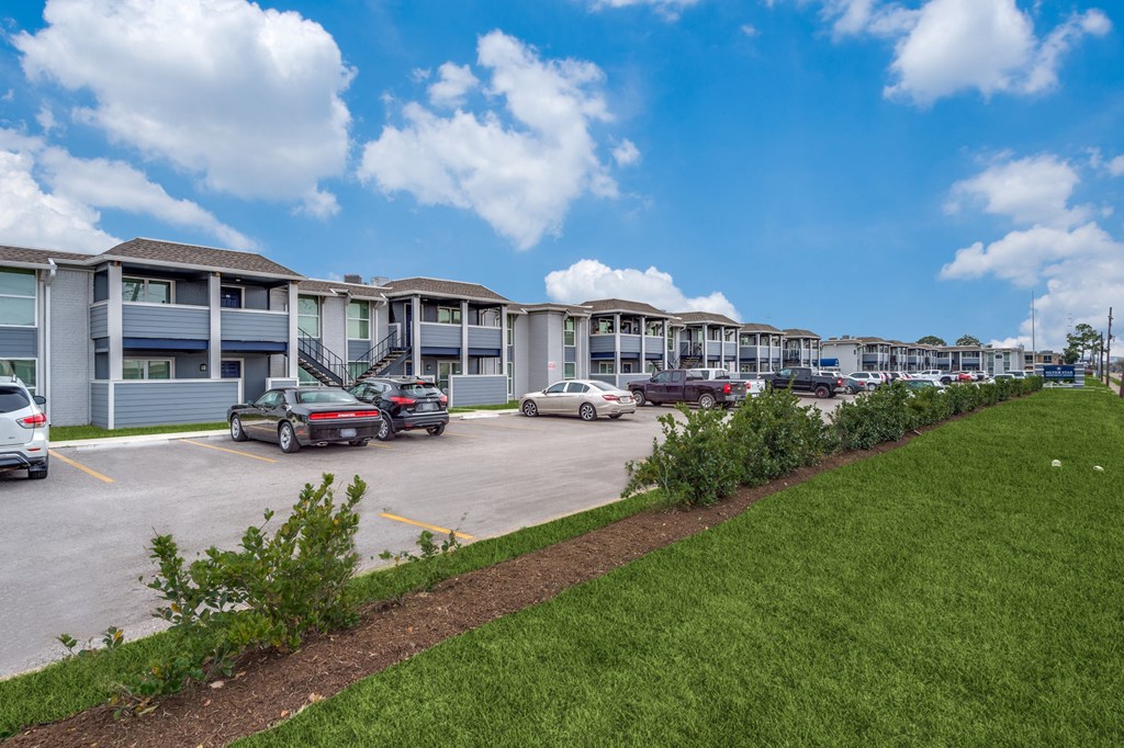 a row of apartments with cars parked in a parking lot