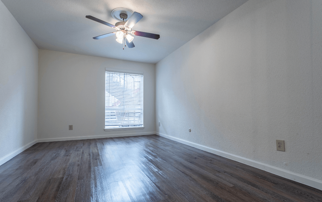 an empty living room with white walls and a ceiling fan